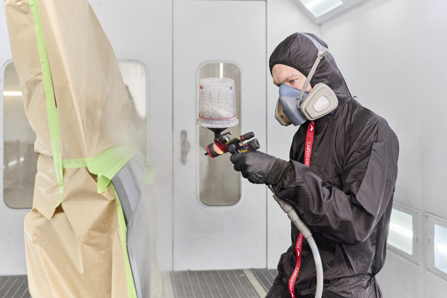 Fahrzeuglackierer bei der Arbeit in der Lackierkabine
